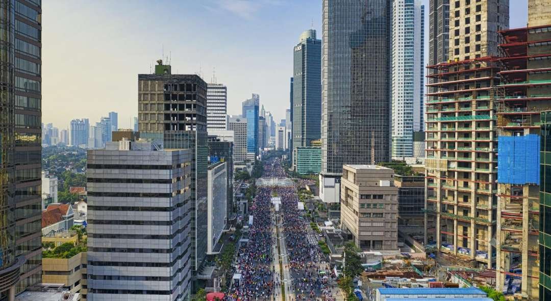 A dynamic aerial view of Jakarta showcasing modern skyscrapers and busy streets under a clear sky.