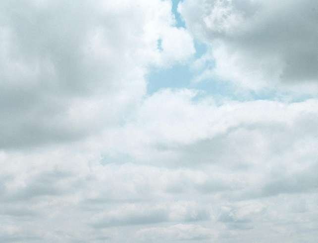 Breathtaking view of a serene grassland under a vibrant blue sky with fluffy clouds.