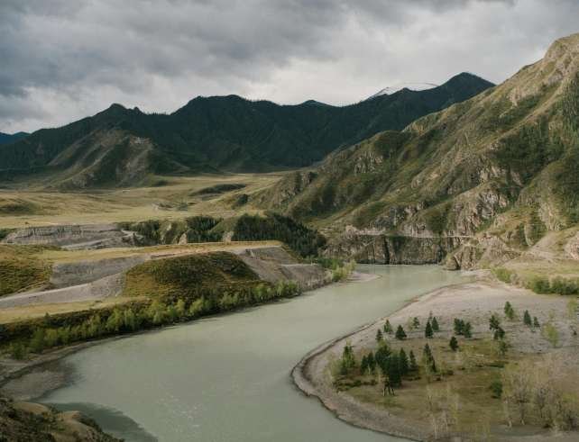 Breathtaking view of a winding river through Mongolian mountains under a cloudy sky.