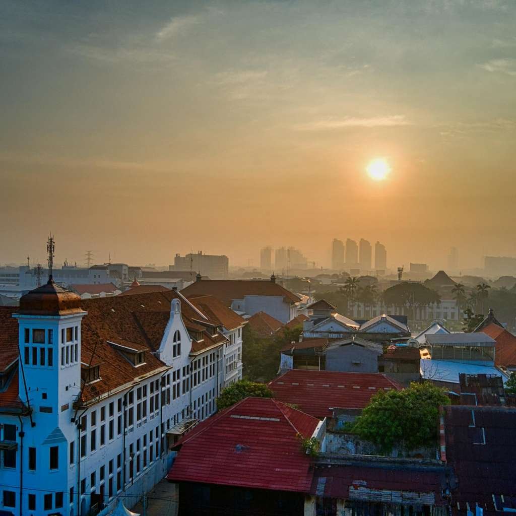 Captivating morning view of Jakarta's historic district with sun rising over iconic rooftops.