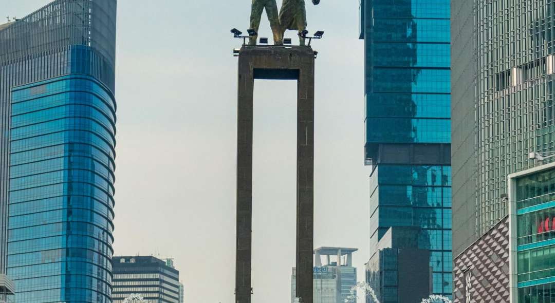 Famous statue surrounded by skyscrapers and fountain in Jakarta, Indonesia.