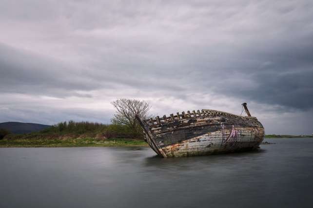 Shipwreck of Bad Eddie on the shore of Magheraclogher Beach under overcast sky in Donegal, Ireland