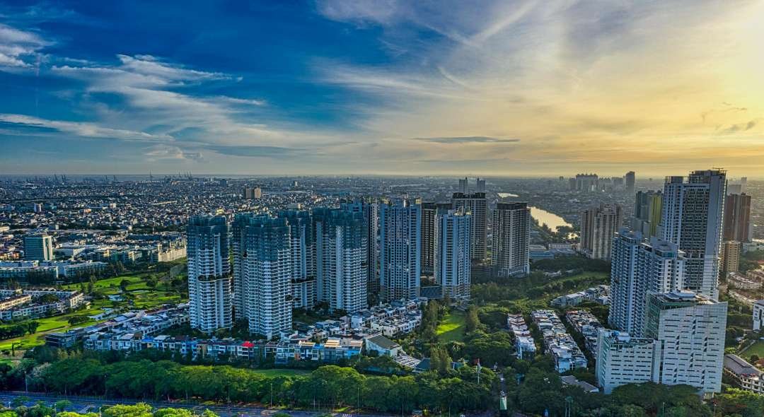 Stunning aerial photograph showcasing Jakarta's urban skyline and greenery at sunset.