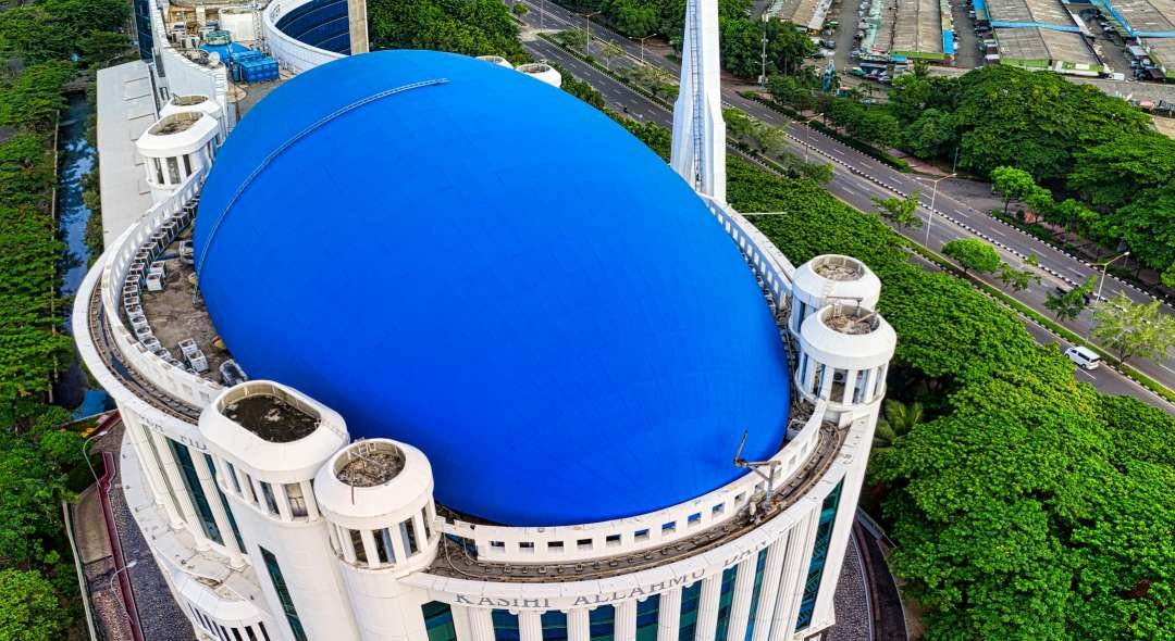 Stunning aerial shot of Istiqlal Mosque with Jakarta skyline in the background, captured in brilliant daylight.